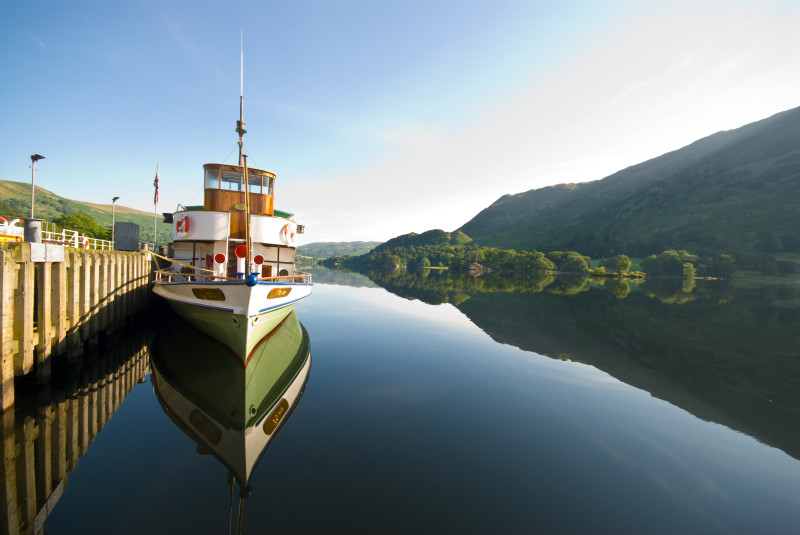 A steamer awaits passengers by the pier at Glenridding, perfectly reflected in the very still waters of tranquil Ullswater. (Photo courtesy of www.cumbriaphoto.co.uk.)